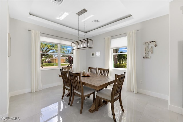 dining room featuring a raised ceiling and light tile patterned floors