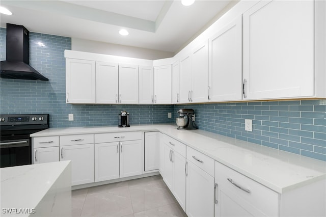 kitchen with black range with electric stovetop, white cabinets, light stone counters, and wall chimney exhaust hood