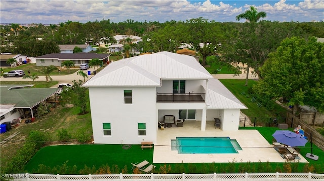 back of property featuring a balcony, a fenced in pool, and a patio area