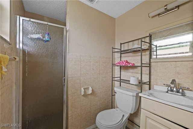 bathroom featuring walk in shower, vanity, a textured ceiling, and tile walls