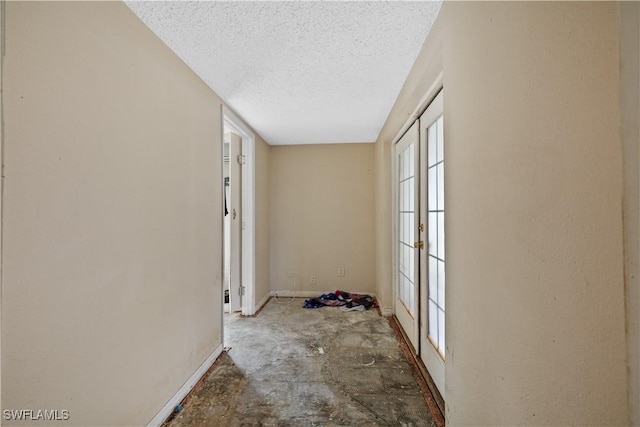 hallway with concrete floors, a textured ceiling, and french doors