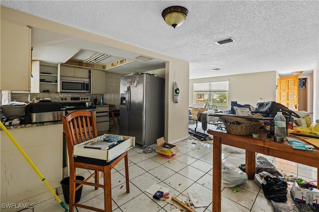 kitchen with light tile patterned flooring, appliances with stainless steel finishes, and a textured ceiling