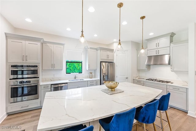 kitchen with a kitchen bar, sink, a center island, appliances with stainless steel finishes, and pendant lighting