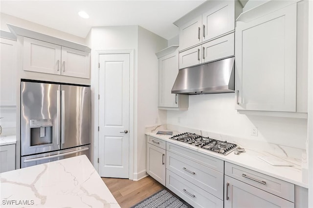 kitchen featuring light stone countertops, appliances with stainless steel finishes, and light hardwood / wood-style floors