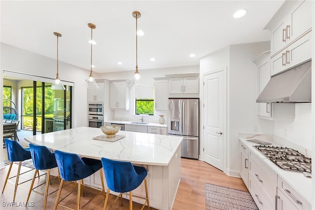 kitchen featuring a breakfast bar area, a center island, pendant lighting, stainless steel appliances, and white cabinets