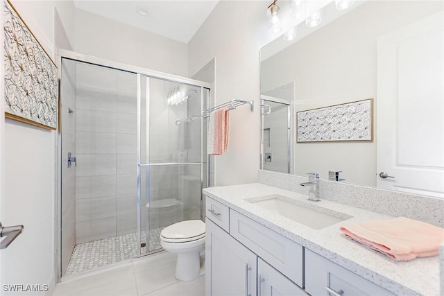 bathroom with vanity, toilet, a shower with shower door, and tile patterned flooring