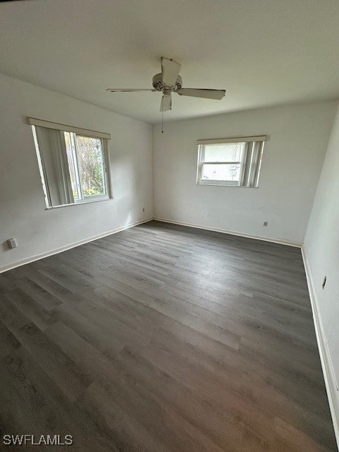 empty room with ceiling fan, a healthy amount of sunlight, and dark hardwood / wood-style floors