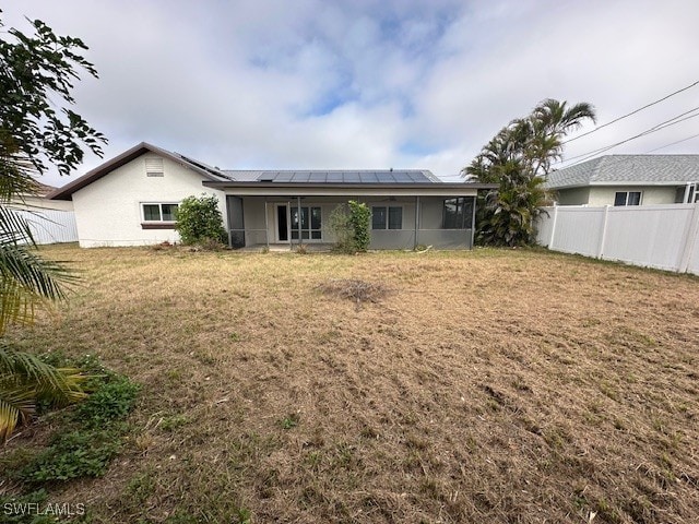 rear view of property with a yard and solar panels