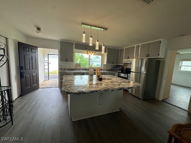 kitchen featuring stainless steel refrigerator, decorative light fixtures, gray cabinetry, stove, and light stone countertops