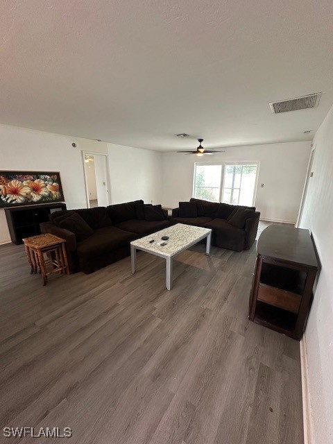 living room featuring ceiling fan and dark hardwood / wood-style floors