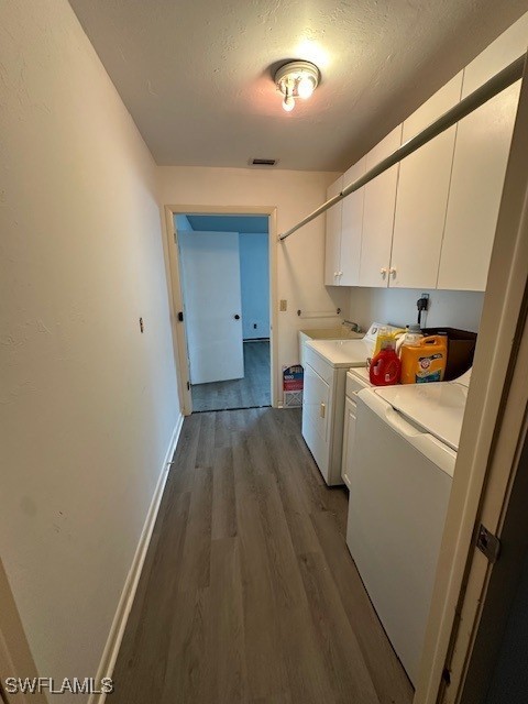 laundry area with dark wood-type flooring, cabinets, washer and dryer, and a textured ceiling