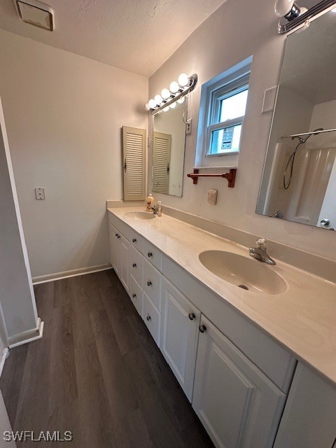 bathroom with hardwood / wood-style flooring, vanity, a textured ceiling, and a shower