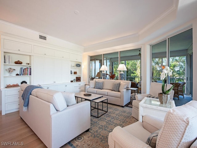 living room with crown molding, built in shelves, and hardwood / wood-style flooring