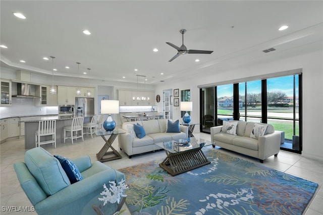 tiled living room with ceiling fan and ornamental molding