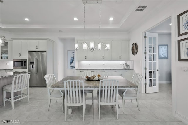 dining room with ornamental molding, a tray ceiling, and a notable chandelier