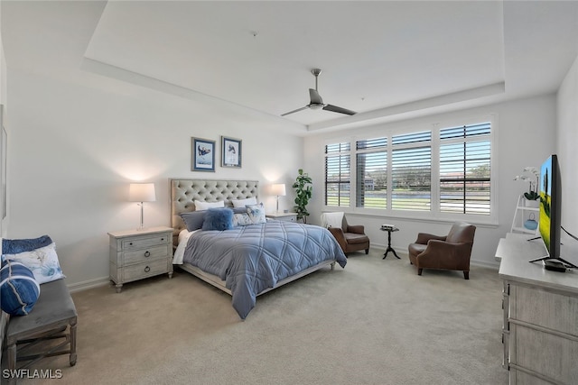 carpeted bedroom featuring a tray ceiling and ceiling fan