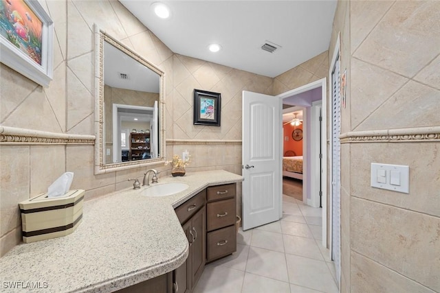 bathroom with tile walls, vanity, and tile patterned flooring