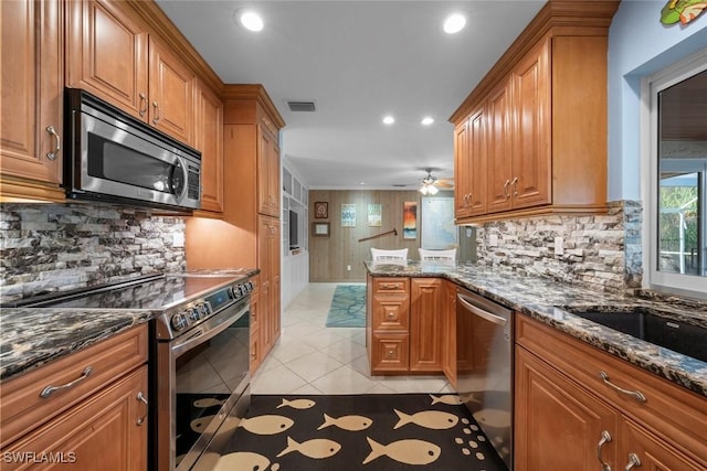 kitchen featuring dark stone countertops, light tile patterned floors, and stainless steel appliances