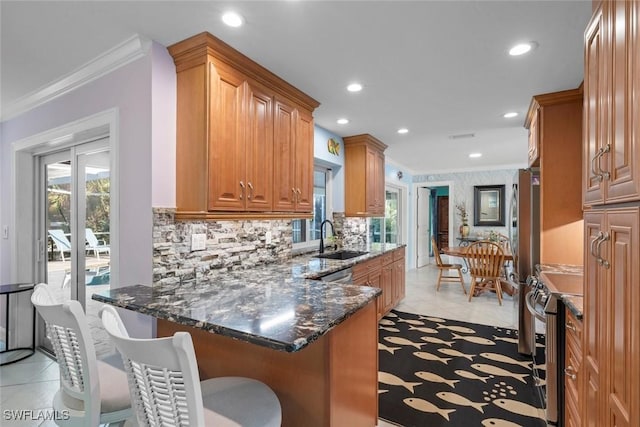 kitchen featuring stainless steel electric range oven, a kitchen bar, sink, and dark stone countertops