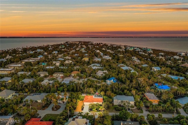 aerial view at dusk featuring a water view