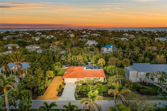 aerial view at dusk featuring a water view