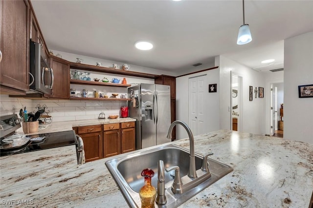 kitchen with appliances with stainless steel finishes, decorative light fixtures, sink, decorative backsplash, and light stone countertops