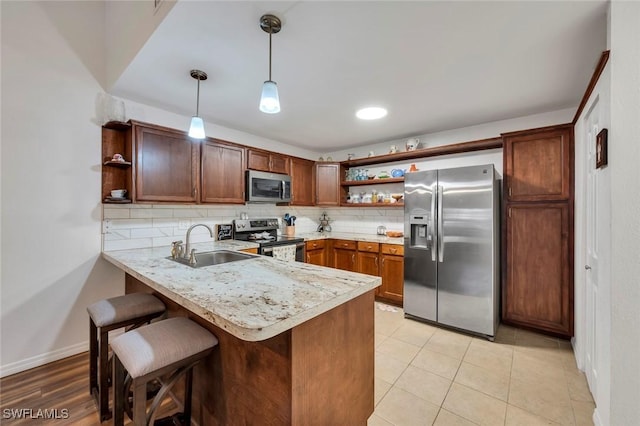 kitchen featuring sink, hanging light fixtures, appliances with stainless steel finishes, kitchen peninsula, and backsplash