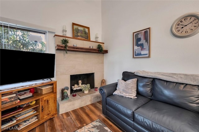 living room featuring dark wood-type flooring and a tiled fireplace