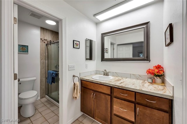 bathroom with tile patterned flooring, vanity, a tile shower, and toilet