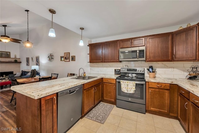 kitchen featuring sink, backsplash, stainless steel appliances, decorative light fixtures, and kitchen peninsula