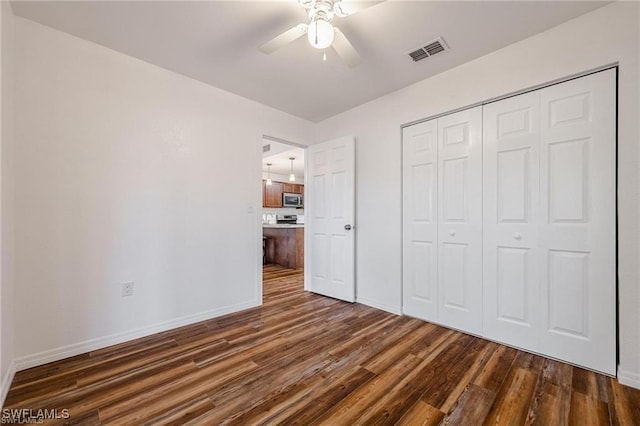 unfurnished bedroom with dark wood-type flooring, ceiling fan, and a closet