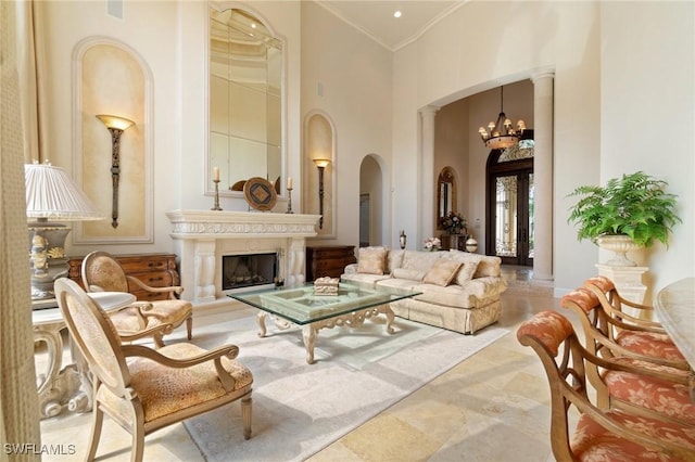 sitting room with arched walkways, ornamental molding, an inviting chandelier, a high ceiling, and a fireplace