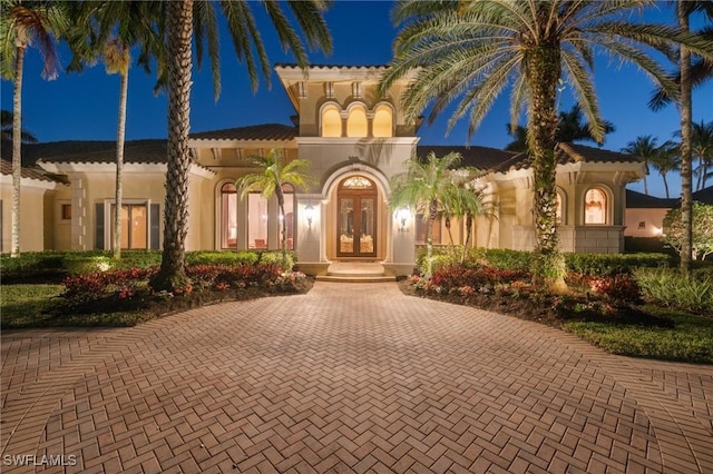 mediterranean / spanish house featuring french doors, a tile roof, and stucco siding