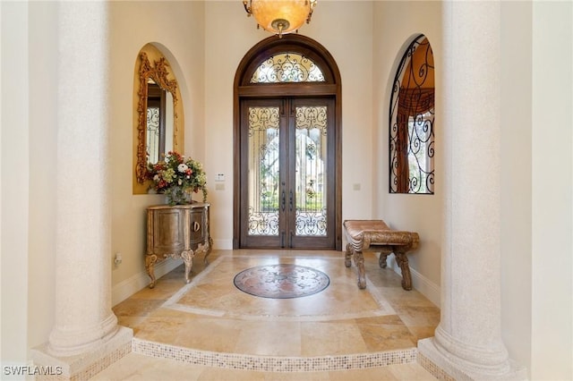 entrance foyer with baseboards, french doors, and ornate columns