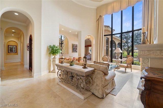 living area featuring arched walkways, crown molding, recessed lighting, a towering ceiling, and baseboards