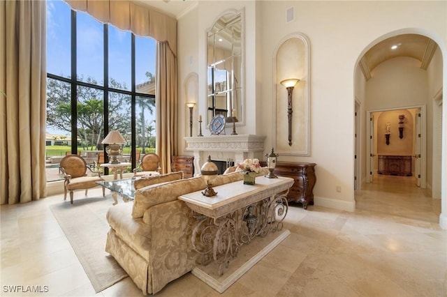 living area featuring arched walkways, visible vents, a towering ceiling, and baseboards