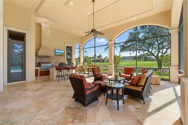 view of patio with glass enclosure, ceiling fan, an outdoor hangout area, a grill, and exterior kitchen