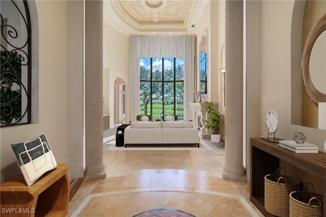 foyer featuring arched walkways, a high ceiling, ornamental molding, a tray ceiling, and decorative columns