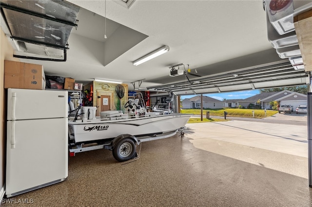 garage with a garage door opener and white refrigerator