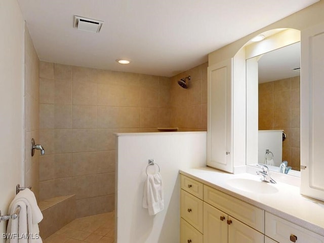 bathroom featuring tiled shower, vanity, and tile walls