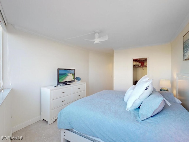 bedroom with light tile patterned flooring, ceiling fan, ornamental molding, and a walk in closet