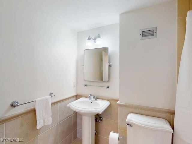 bathroom with sink, tile walls, and toilet