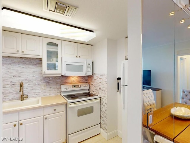 kitchen featuring sink, backsplash, white cabinets, and white appliances