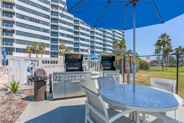 view of patio featuring exterior kitchen, grilling area, outdoor dining area, and fence