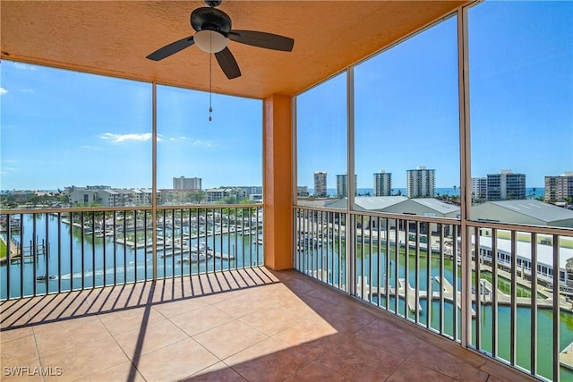 sunroom featuring ceiling fan and a water view