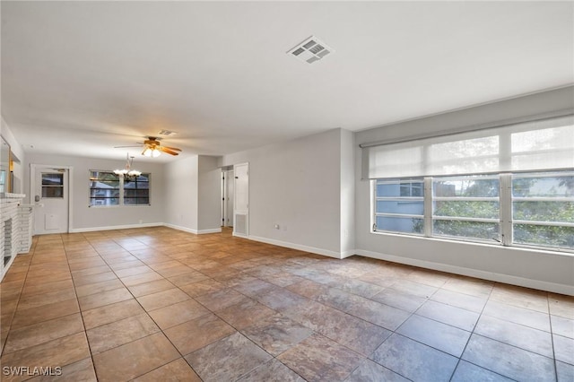 unfurnished living room featuring light tile patterned floors, ceiling fan with notable chandelier, and plenty of natural light