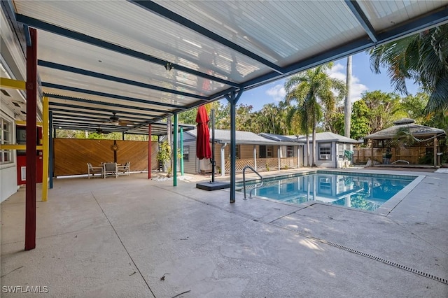 view of swimming pool featuring an outbuilding, a patio area, and ceiling fan