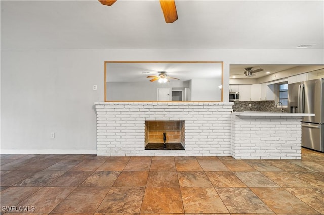 unfurnished living room with sink, a fireplace, and ceiling fan