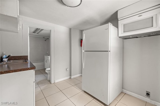 kitchen with white cabinetry, sink, light tile patterned flooring, and white appliances