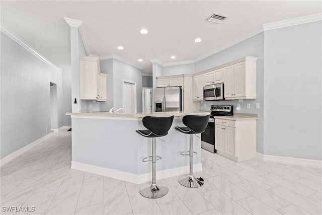 kitchen with cream cabinetry, ornamental molding, a breakfast bar, and appliances with stainless steel finishes